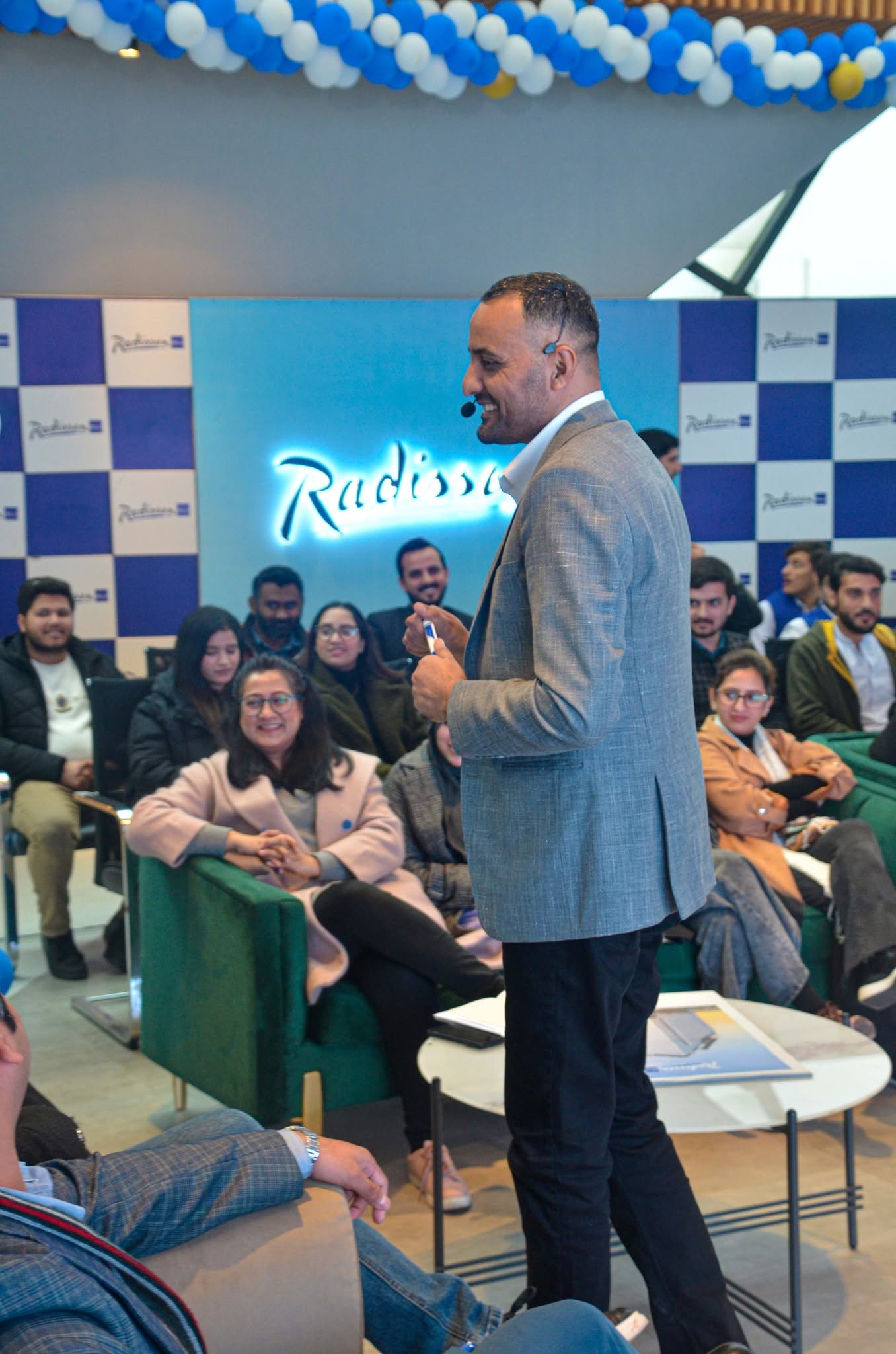 Khawar with a headset microphone speaking to a seated audience at an invited session