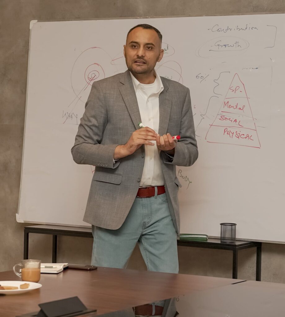 Khawar mid-explanation at a whiteboard covered in his own diagrams, markers in hand